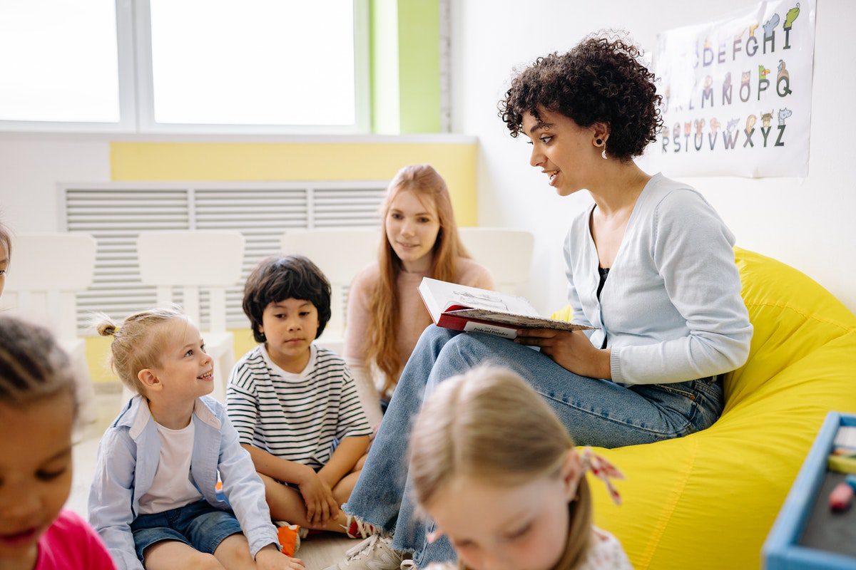 A teacher reading a book for her students. Early Childhood Education Associate Degrees