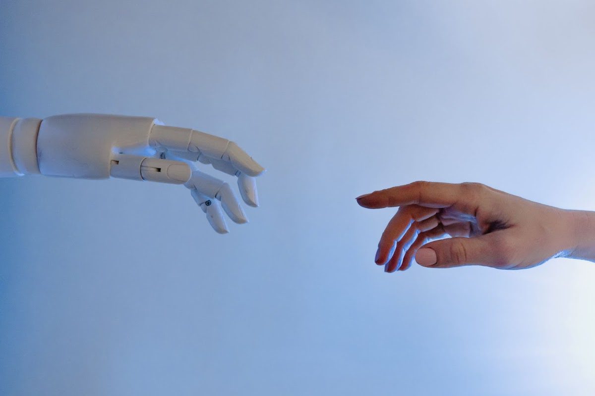 A robot hand and a human hand reaching toward each other. 