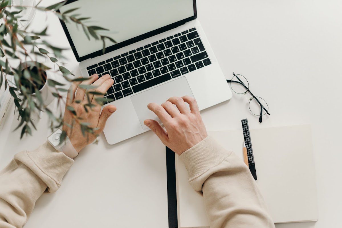 A person working on a laptop resting on a white desk.