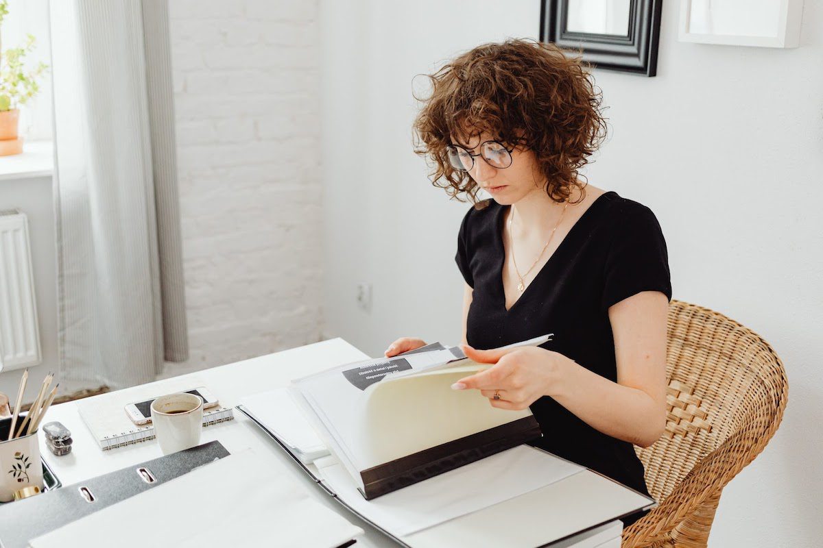 A woman at a desk reading a notebook.