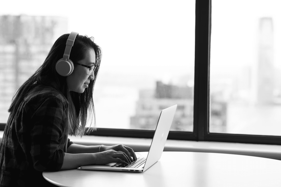 Woman coding while sitting next to a window.