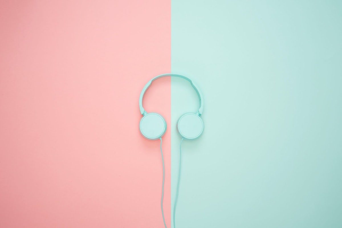 Blue headphones on a pink and blue background.