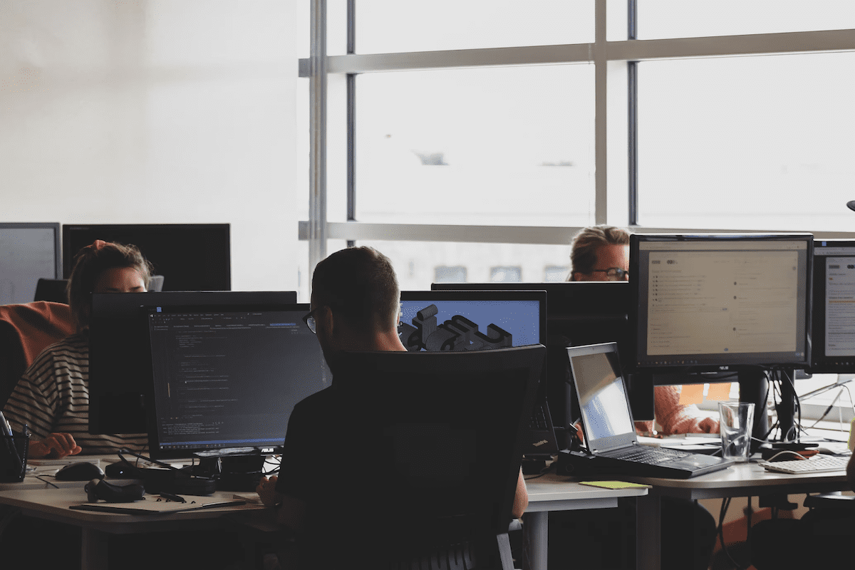 three people working on information security controls in a shared office.