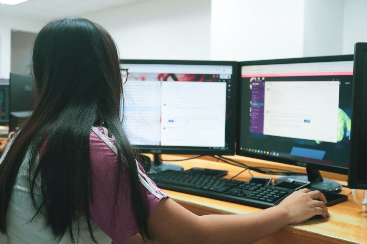 A web developer uses two monitors at a workstation to use various programs