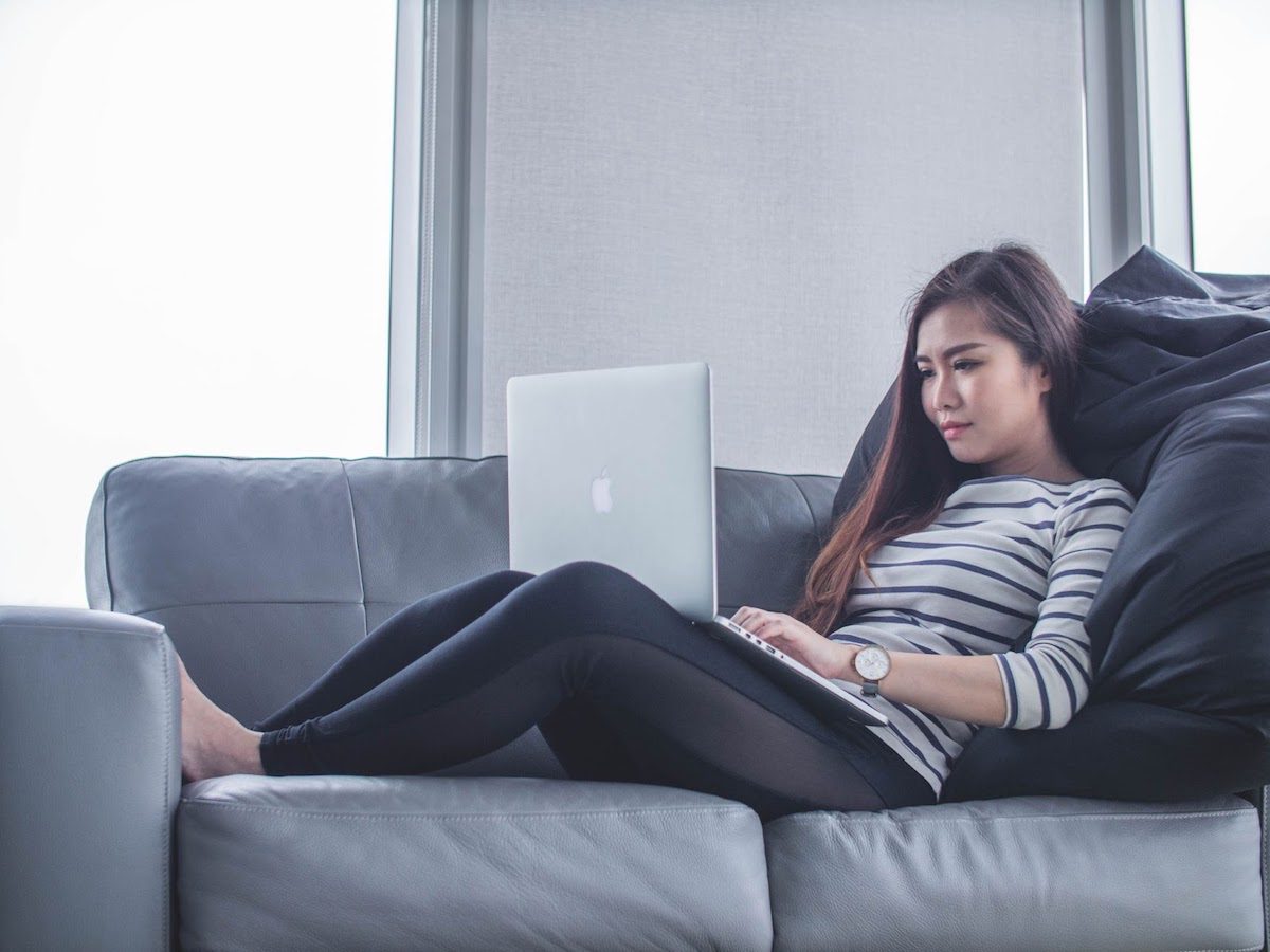 a woman sitting on a couch and working on her laptop  Online Django Courses, Classes, and Training