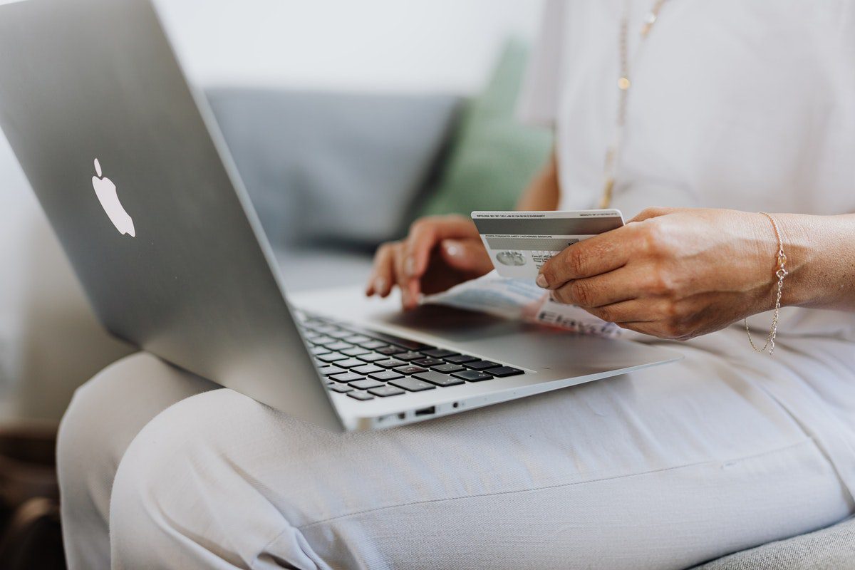 A person holding a credit card and using a laptop Online Shopify Courses