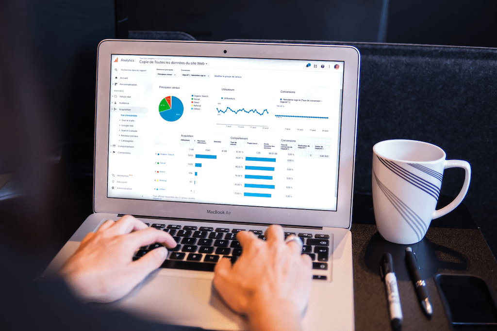 Person typing on a laptop to analyze charts and graphs