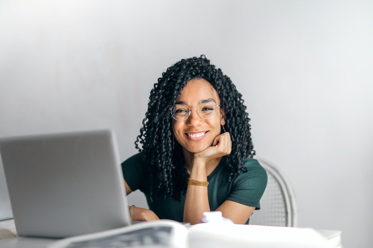 Woman smiling and sitting in front of a laptop computer.  Online Hadoop Courses