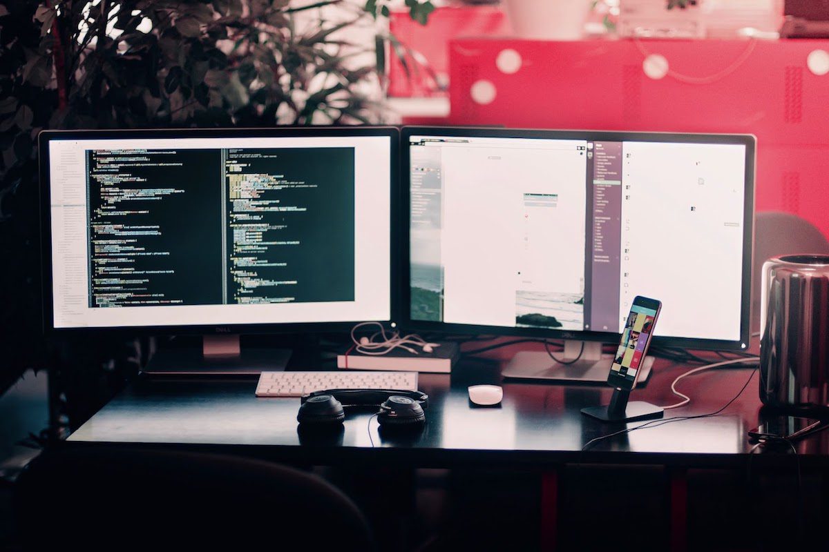 Work desk showing two computer monitors displaying code and a web development project