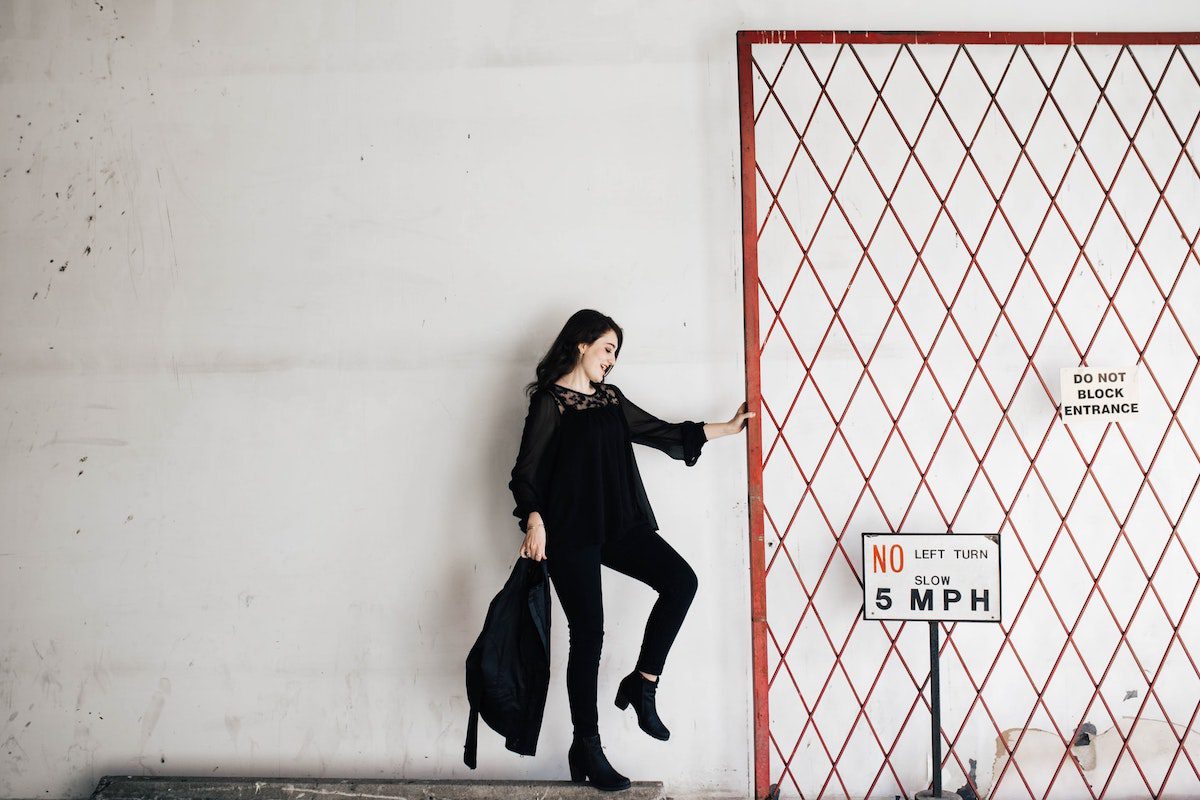 A woman wearing all black standing next to a red gate. Fun Careers