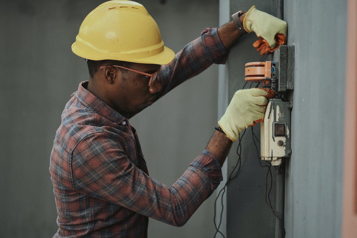 Electrician wearing a yellow helmet and adjusting cables. Futureproof Careers