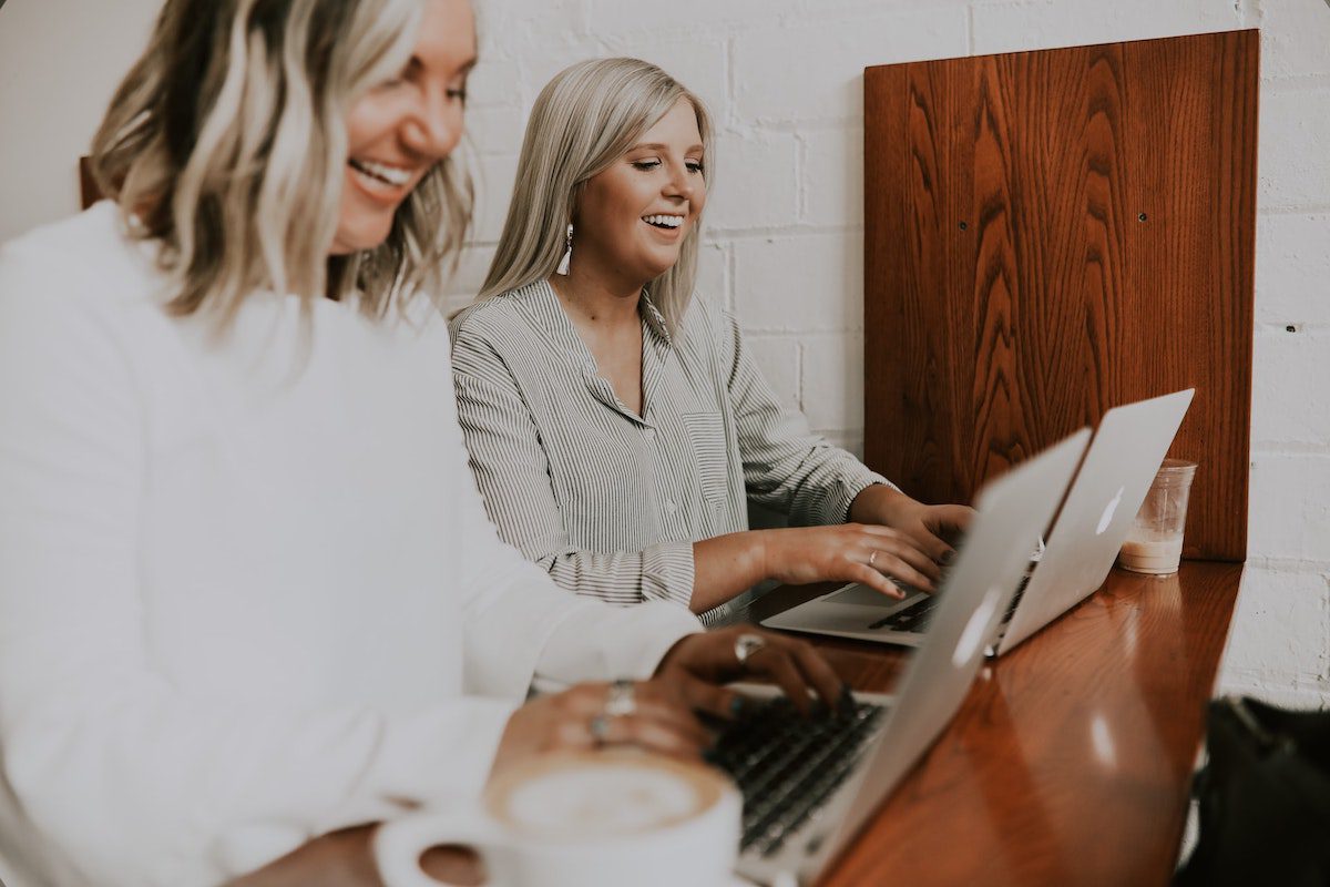 Two women working on their laptops and laughing. Highest Paying Careers