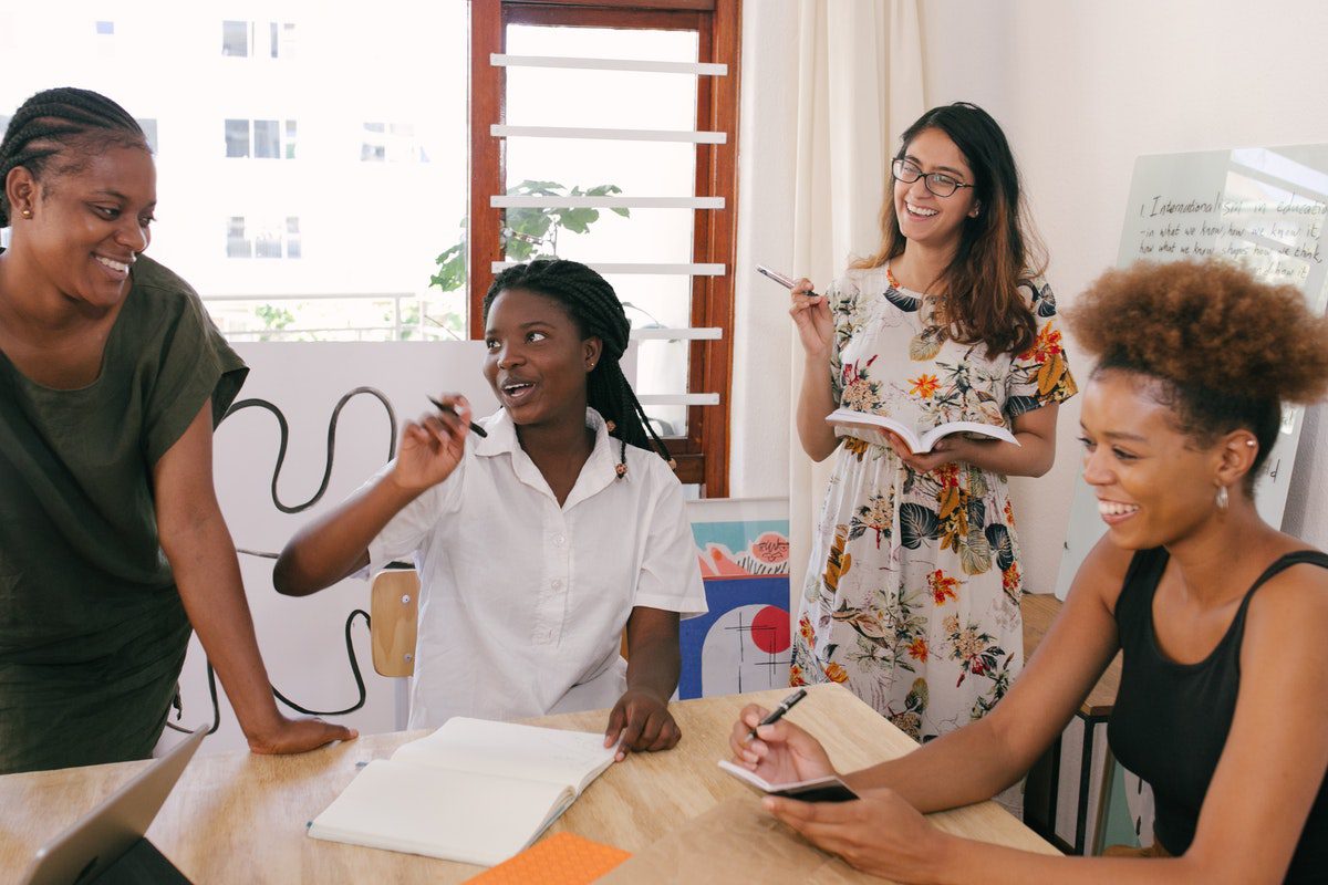 Four women gathered around a table taking notes and smiling. Satisfying Careers