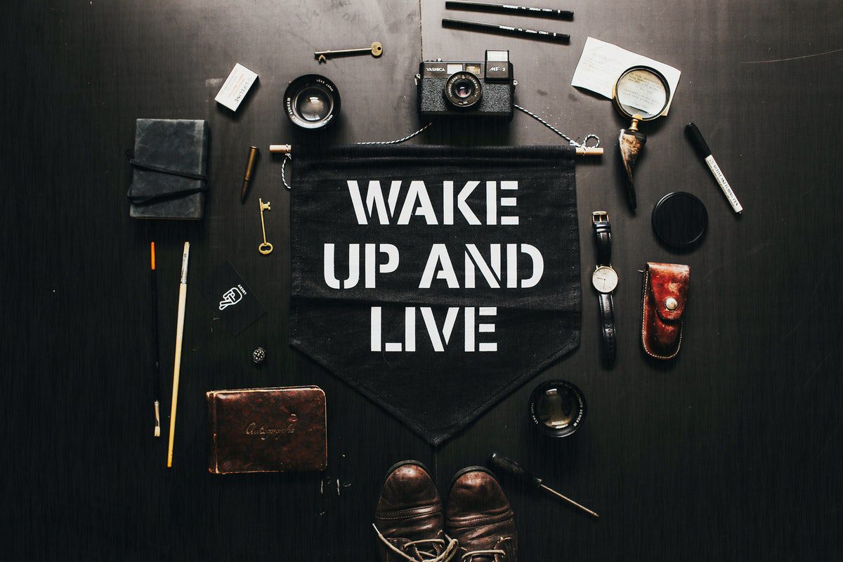 Various supplies around a black sign with an inscription that says, ‘wake up and live.’ Work From Home Careers