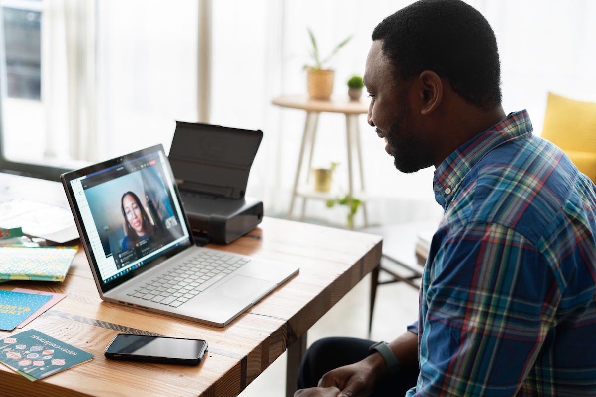 A man sitting in front of a laptop attending an online meeting. The Best Brown Online Courses