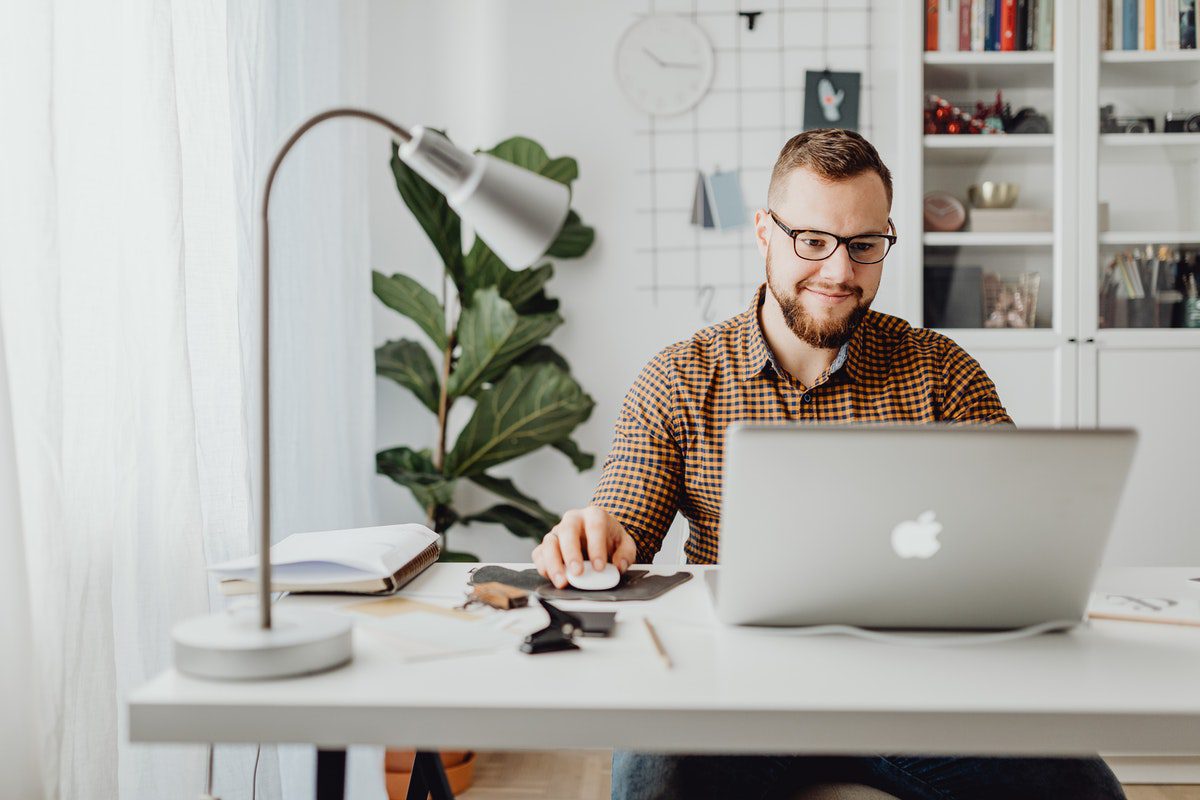 A person at their desk using a Macbook to find remote jobs that don’t require a degree