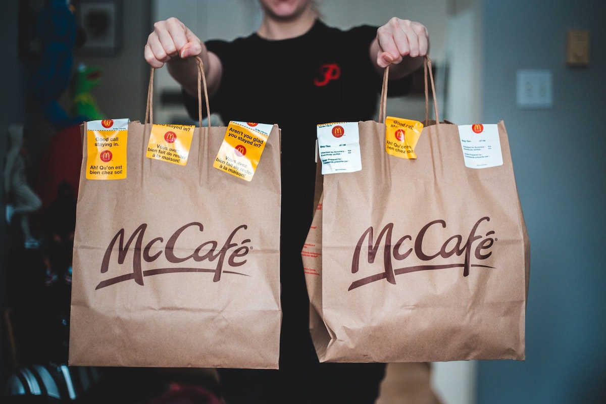 A person holding two McDonalds bags How to Become a DoorDash Delivery Driver