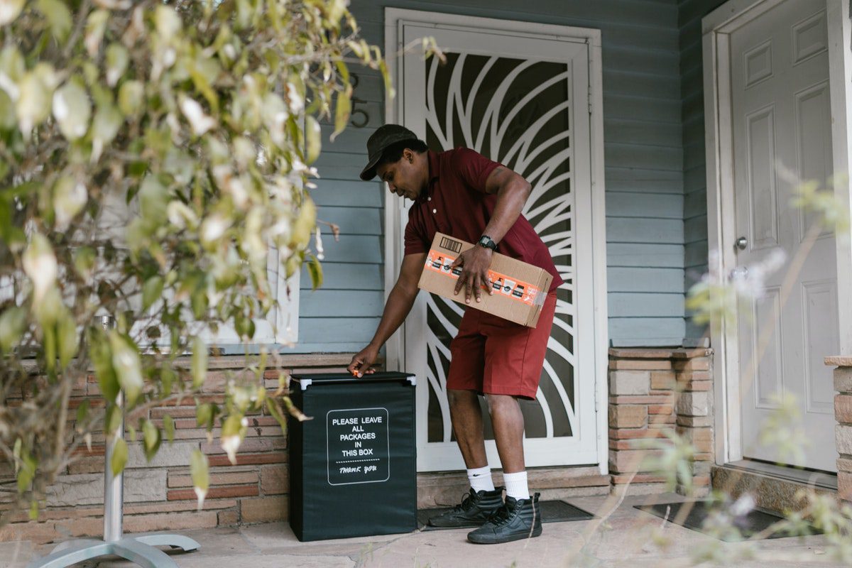 A man dropping off a delivery with a package in hand. How to Become a Shipt Shopper