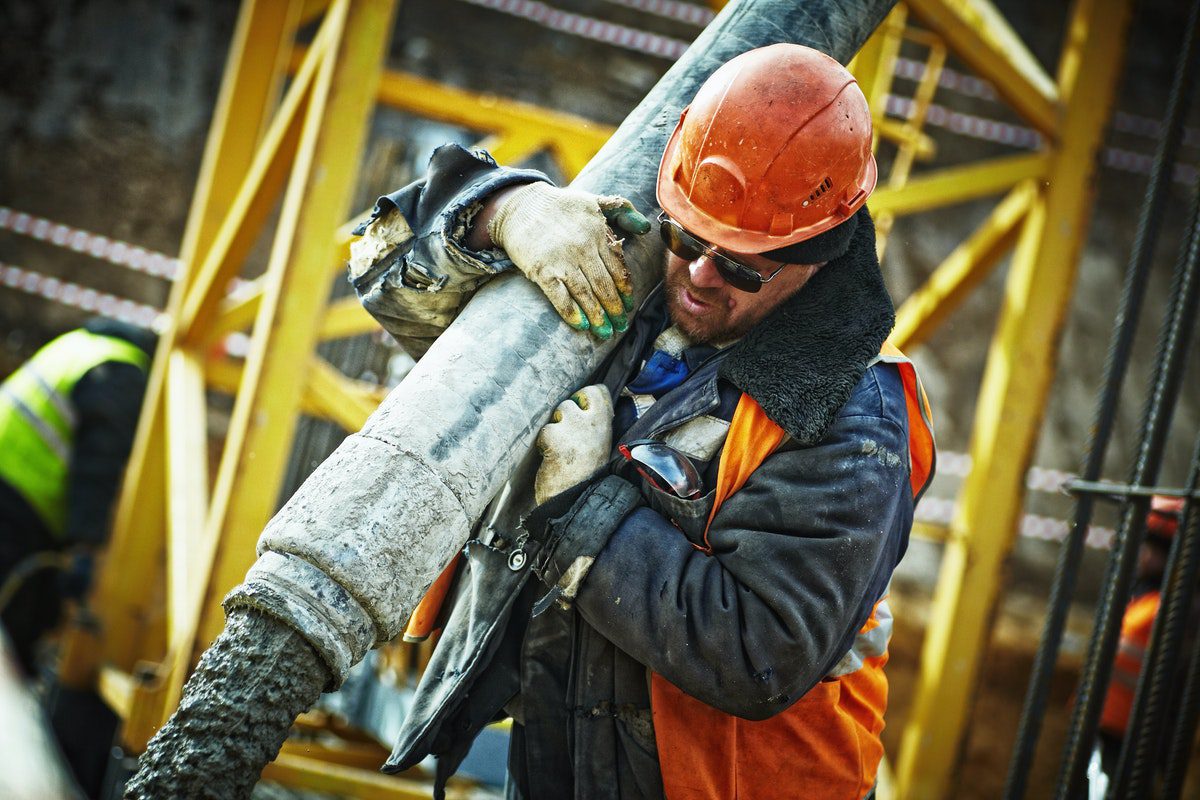 A construction worker carrying a grey pipe. Jobs That Pay More Than Minimum Wage