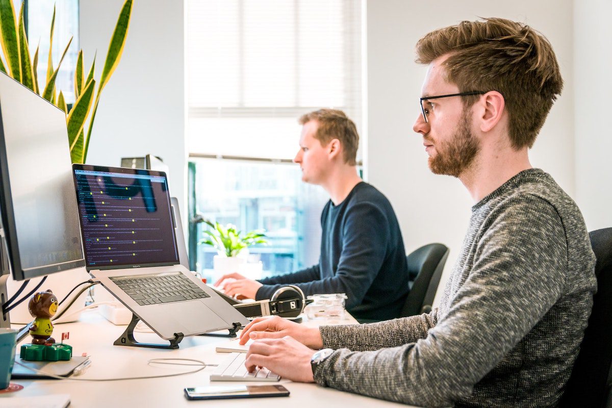 Two men working on computers next to each other in an office. Data Analyst Job Satisfaction