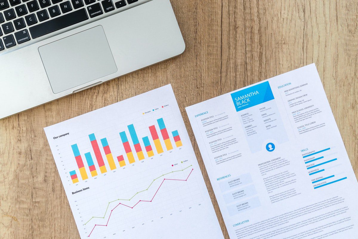 a resume sample and company growth chart laid out in front of a laptop. Registered Nurse Cover Letter