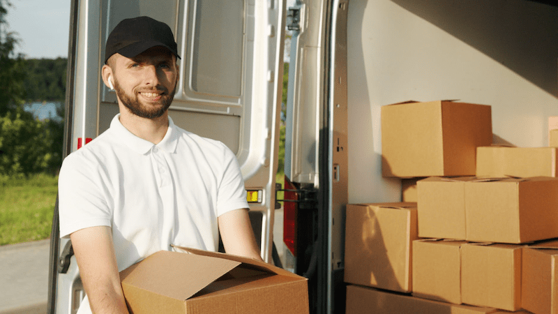 Man in a white shirt and black cap smiling while making deliveries