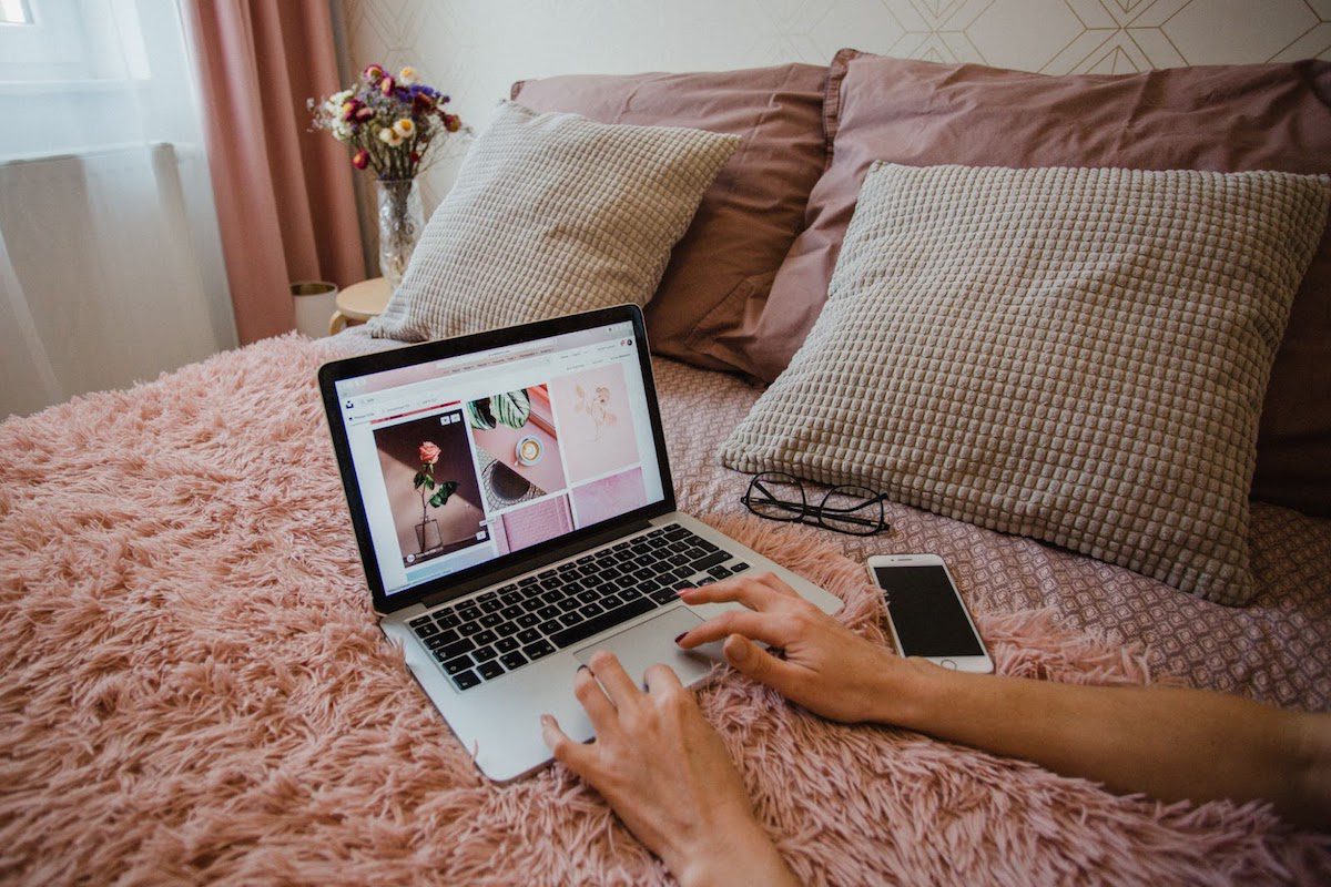 A person working on a laptop on a bed