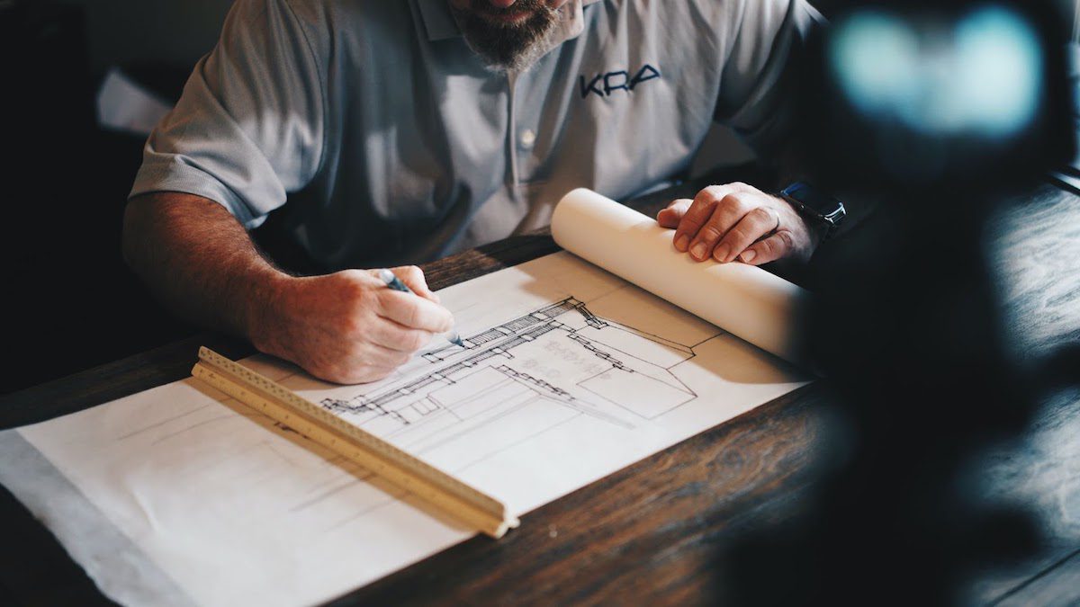 Person drawing blueprints at a desk Masters Of Architecture Scholarships