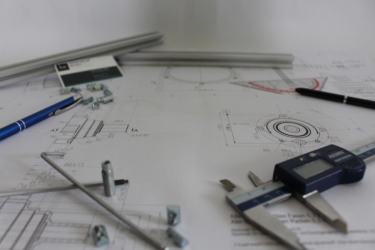 Paper filled with technical drawing and various technical tools scattered around Masters Of Engineering Scholarships