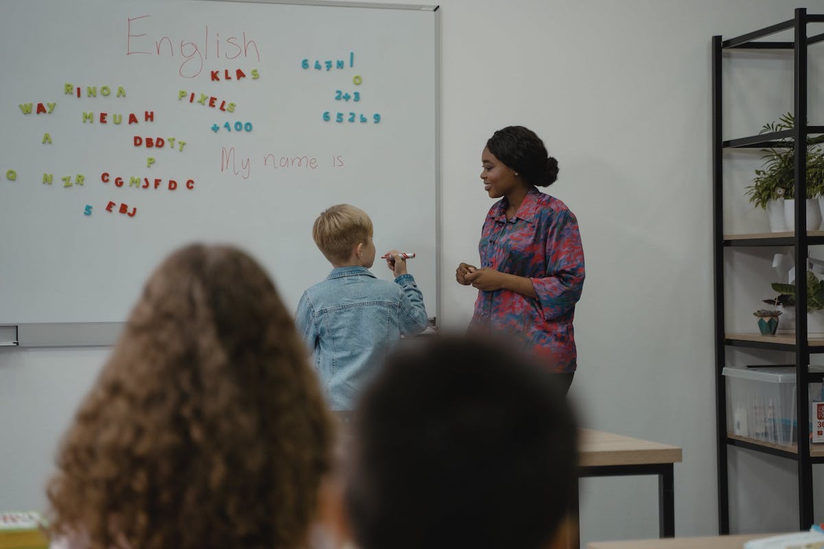 A child and teacher standing in front of a whiteboard. Masters In Special Education Scholarships