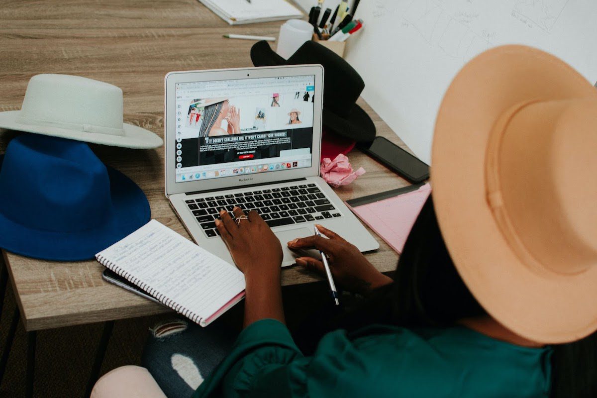 A person using a laptop surrounded by fashion accessories