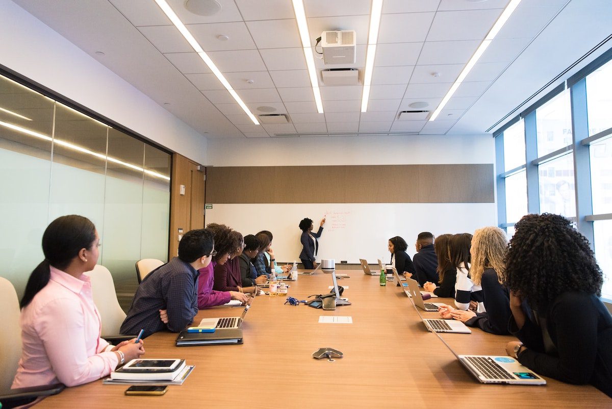 Business professionals at a conference table listening to someone give a presentation.