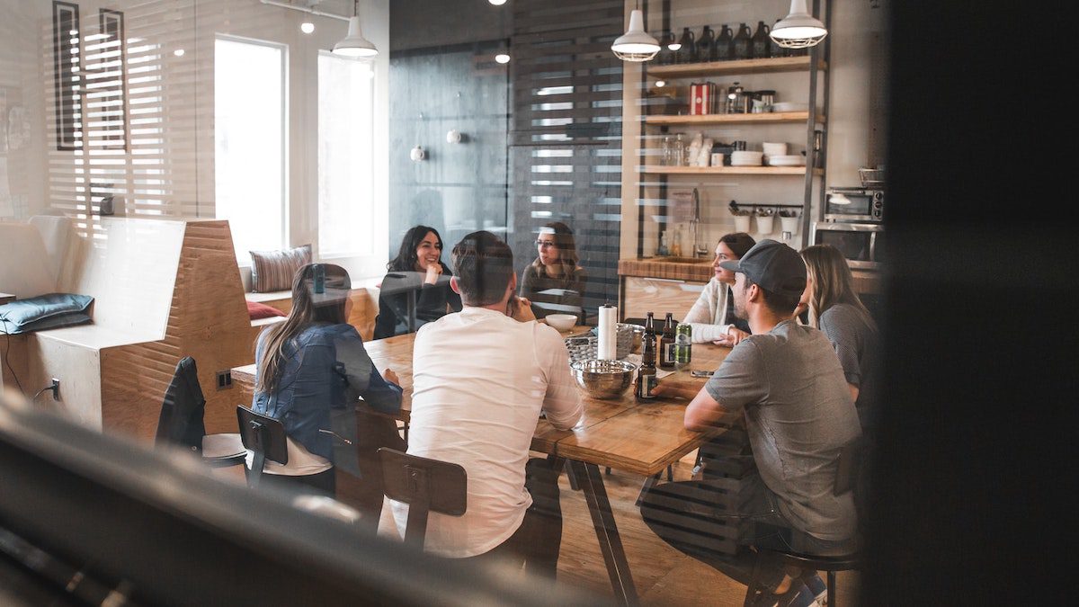 Several young people sitting around a table in a restaurant.  Jobs That Pay $14 An Hour