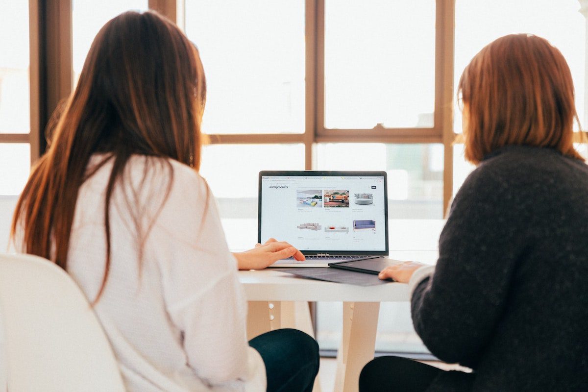 Two women looking at a laptop looking for jobs at Amazon.