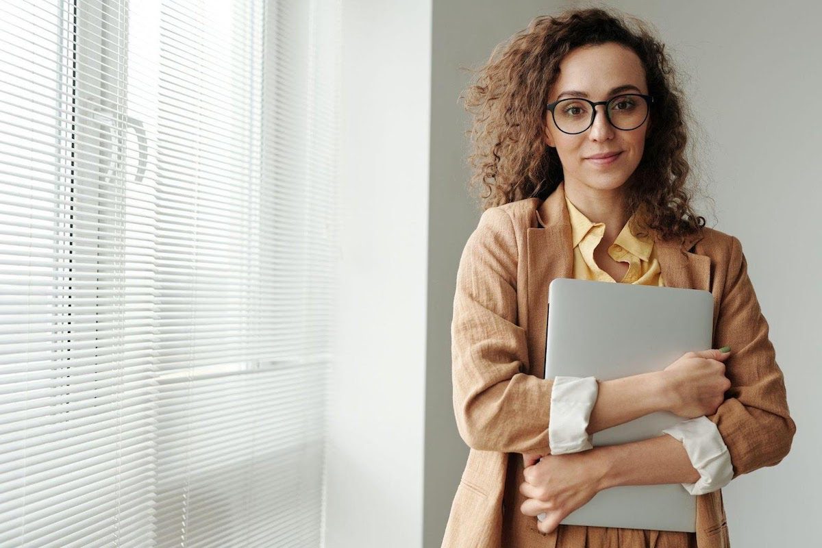 a woman holding a laptop after she has finished writing a sales manager cover letter