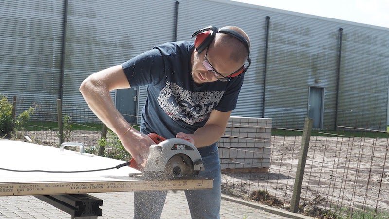 A handyman cutting wood with protective gear 