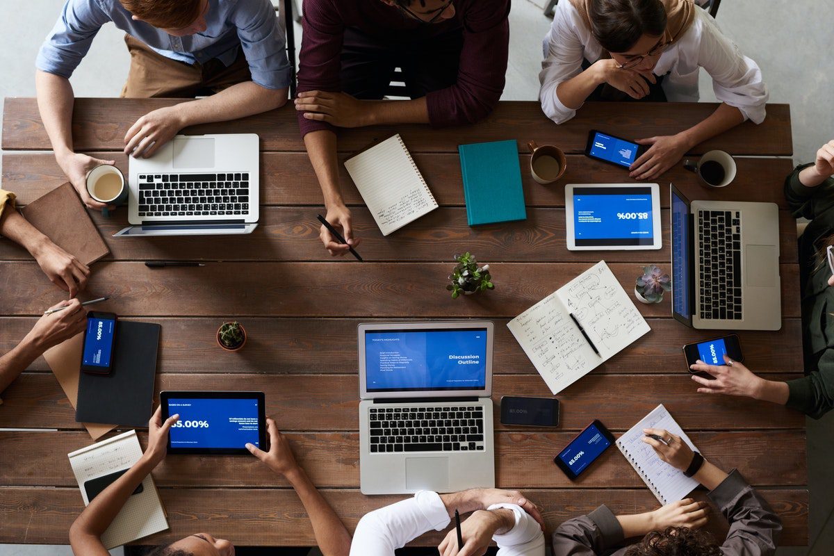 A team of professionals working on their laptops around a table.  Agile Best Practices