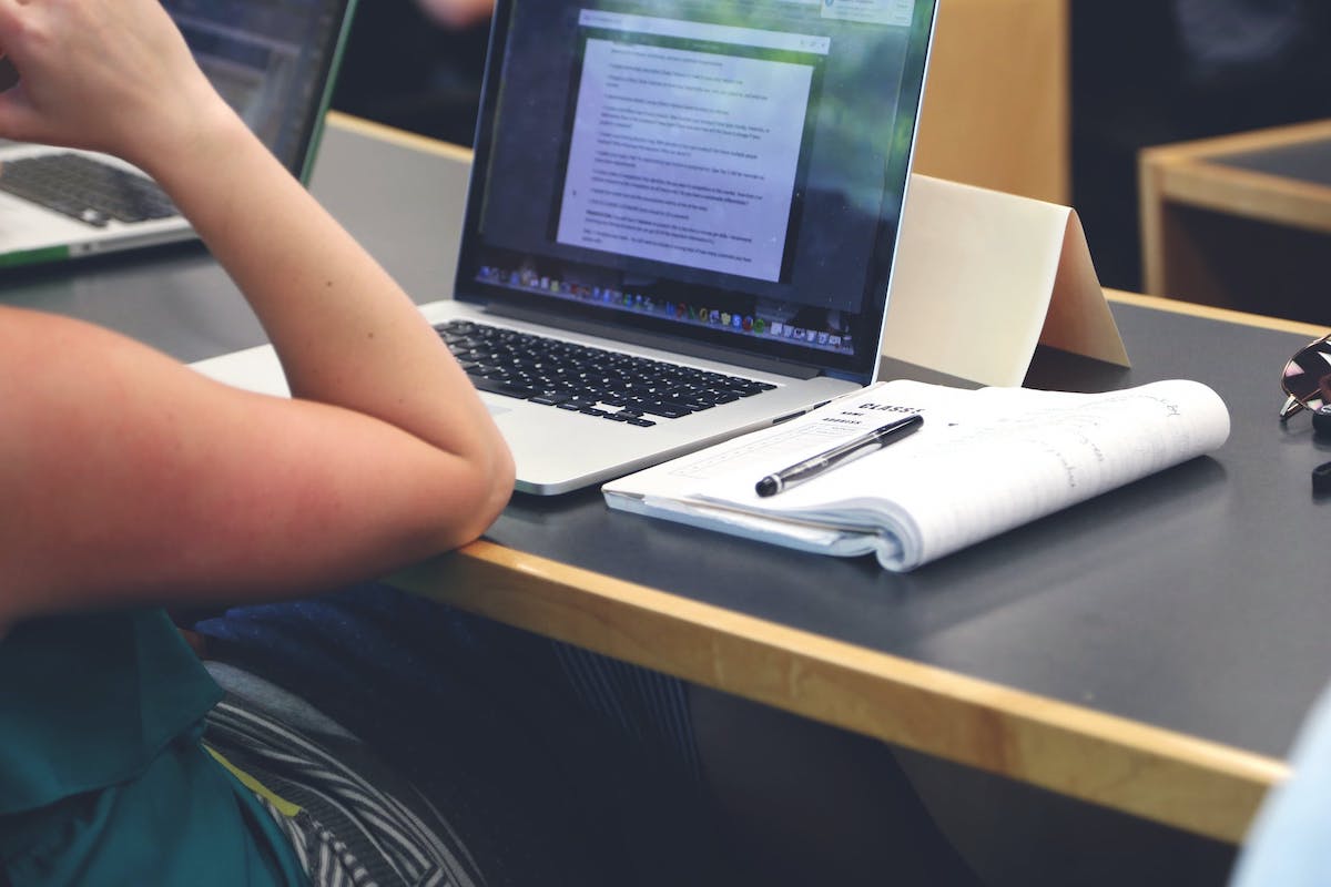  A woman working on her laptop with a notebook lying open next to her.  AWS Best Practices