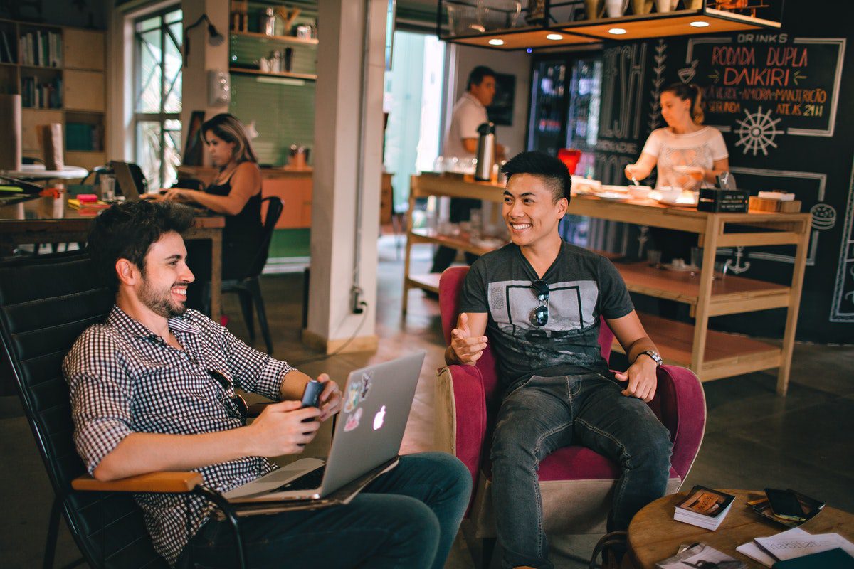 Two people sitting in chairs having a conversation with a laptop open. Entry Level Product Manager Jobs