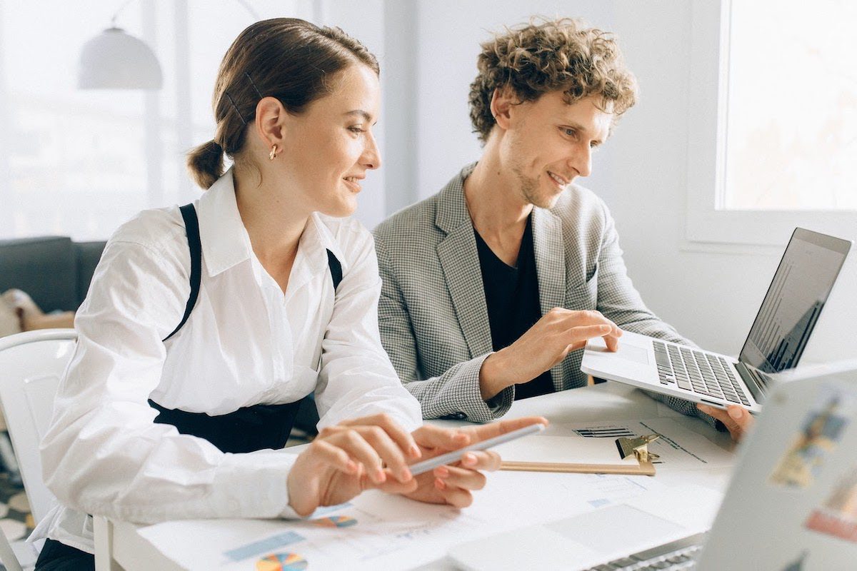 Two functional analysts monitoring market trends on a laptop.