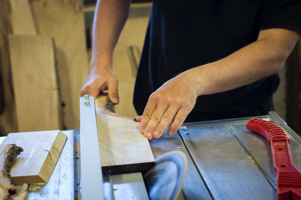 Person cutting a plank of wood with an electric saw 