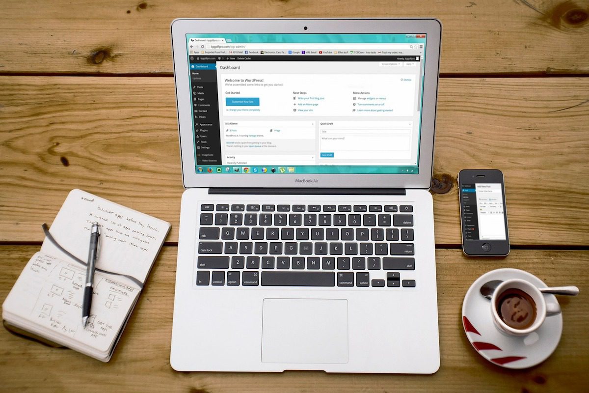 Laptop displaying a WordPress page next to a notebook on a desk