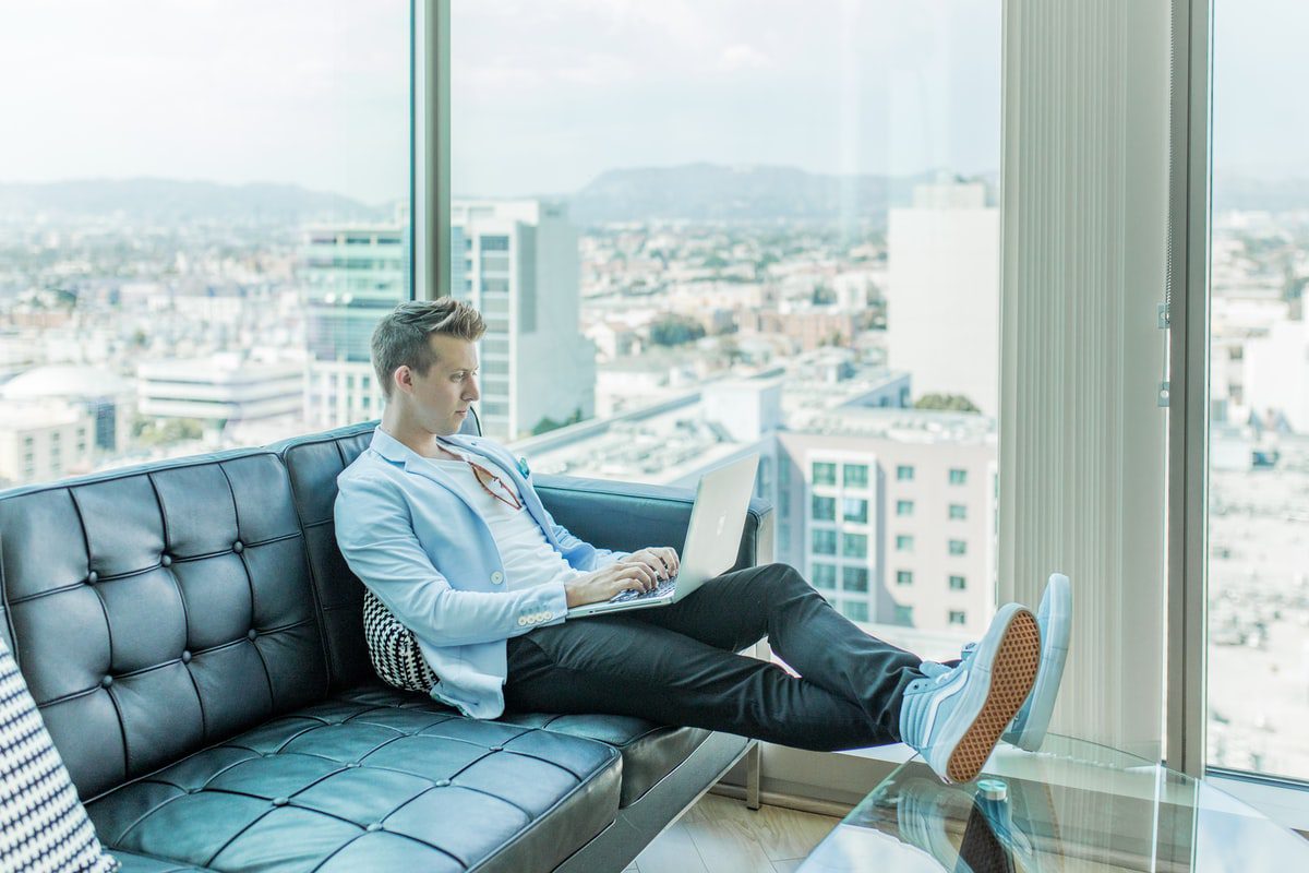 Man sitting on the couch with a laptop on his lap.