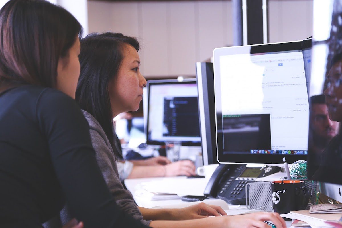 two women working on a desktop computer