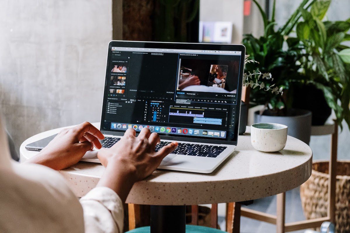 A person sitting at a table editing a picture on a laptop