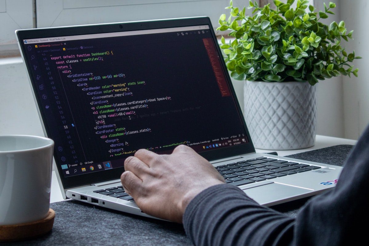 A man writing lines of code on a laptop 