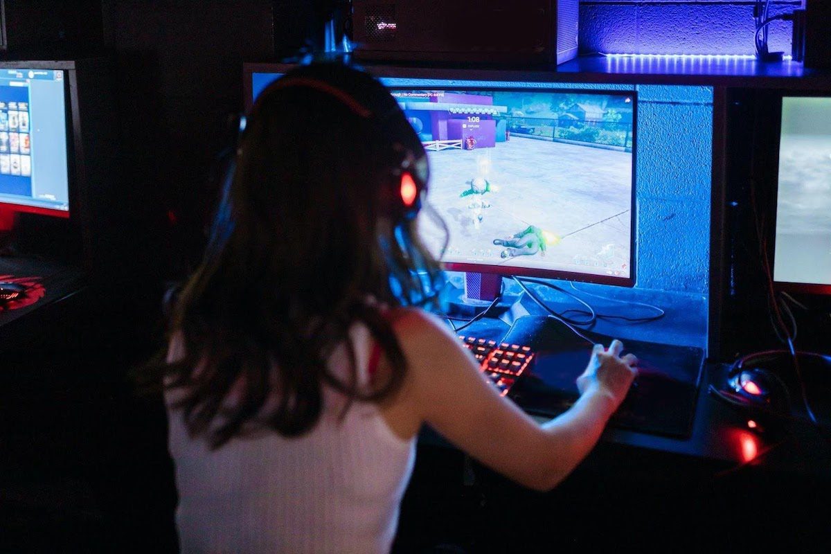 A female gamer wearing headphones and playing a computer game