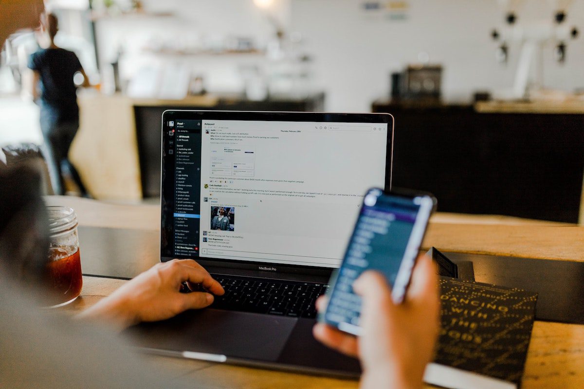 A man looking glancing over his Slack channel while scrolling his phone. Codesmith Interview Questions