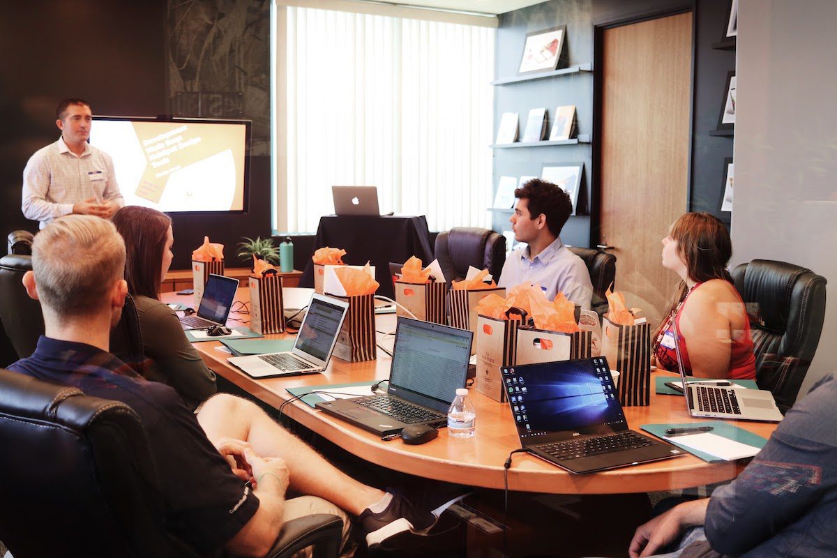 A man giving a presentation for a group of people sitting in a boardroom. 