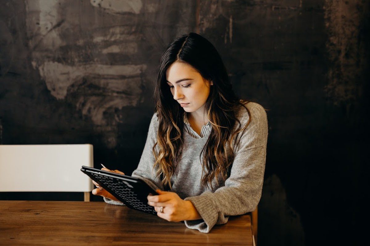 A woman sitting at a table working on a tablet.